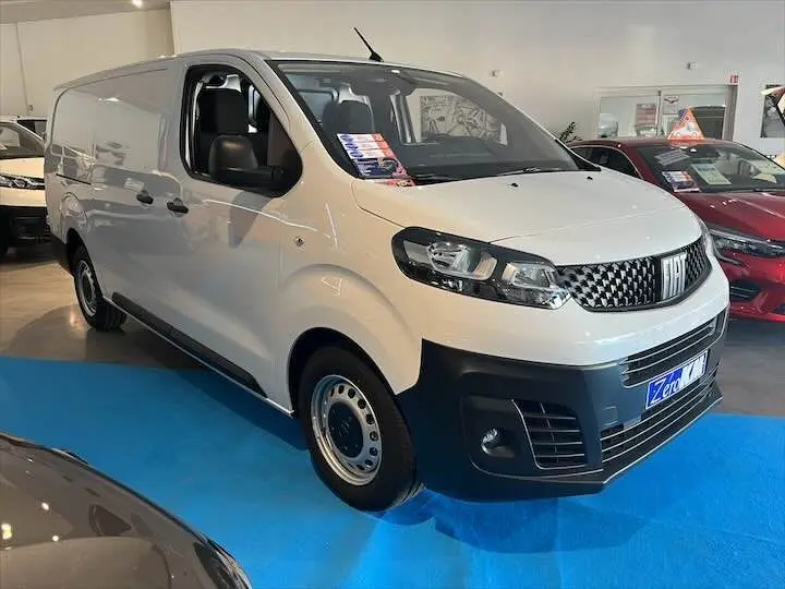 Fourgon FIAT Scudo blanc vu en 3/4 avant droit dans un showroom avec calandre noire et jantes acier.