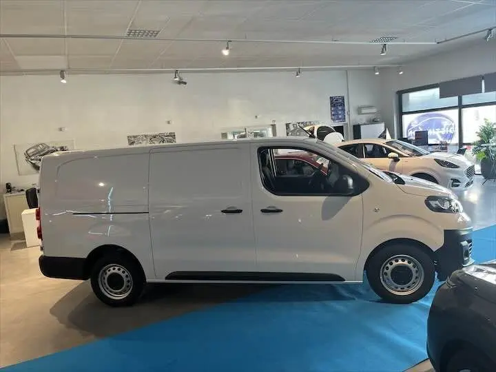 Fiat Scudo Fourgon blanc vu de profil côté gauche, stationné en intérieur sur sol bleu.
