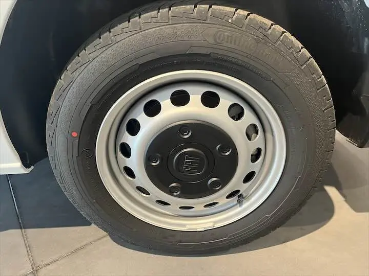 Gros plan sur la roue avant droite d'un FIAT Scudo Fourgon blanc avec jante acier et logo FIAT central.