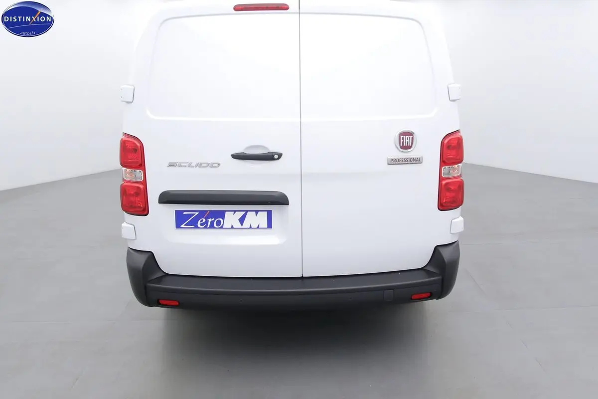 Vue arrière du FIAT Scudo Fourgon blanc avec logo et plaque Zéro KM dans un studio lumineux.