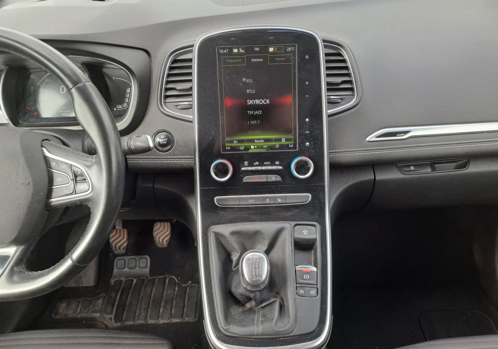 Vue intérieure centrée sur la console centrale et le levier de vitesse manuel du Renault Scenic IV gris platine.