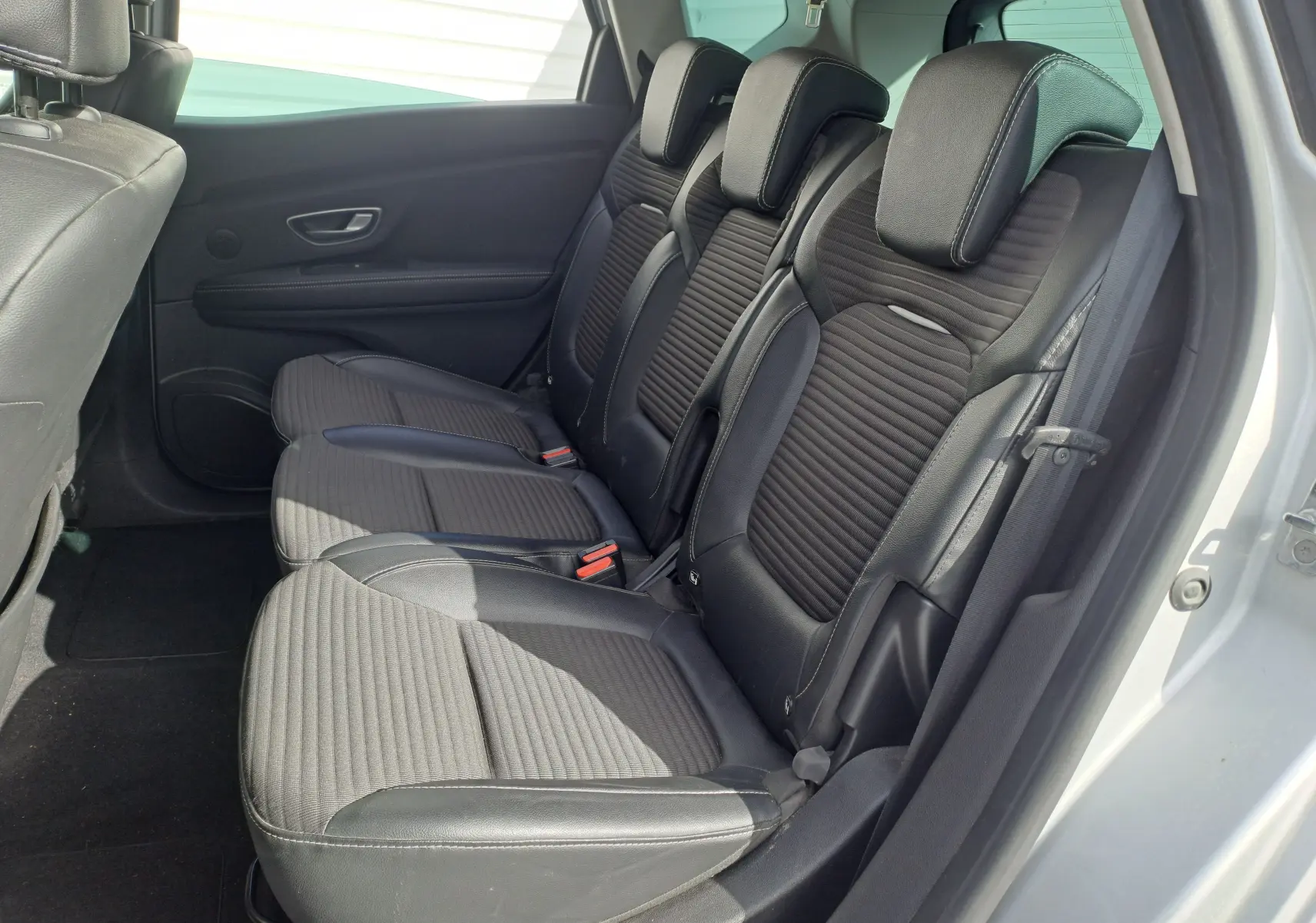 Vue latérale des sièges arrière en cuir noir du Renault Scenic IV gris platine, avec appuie-têtes et ceinture de sécurité visible.