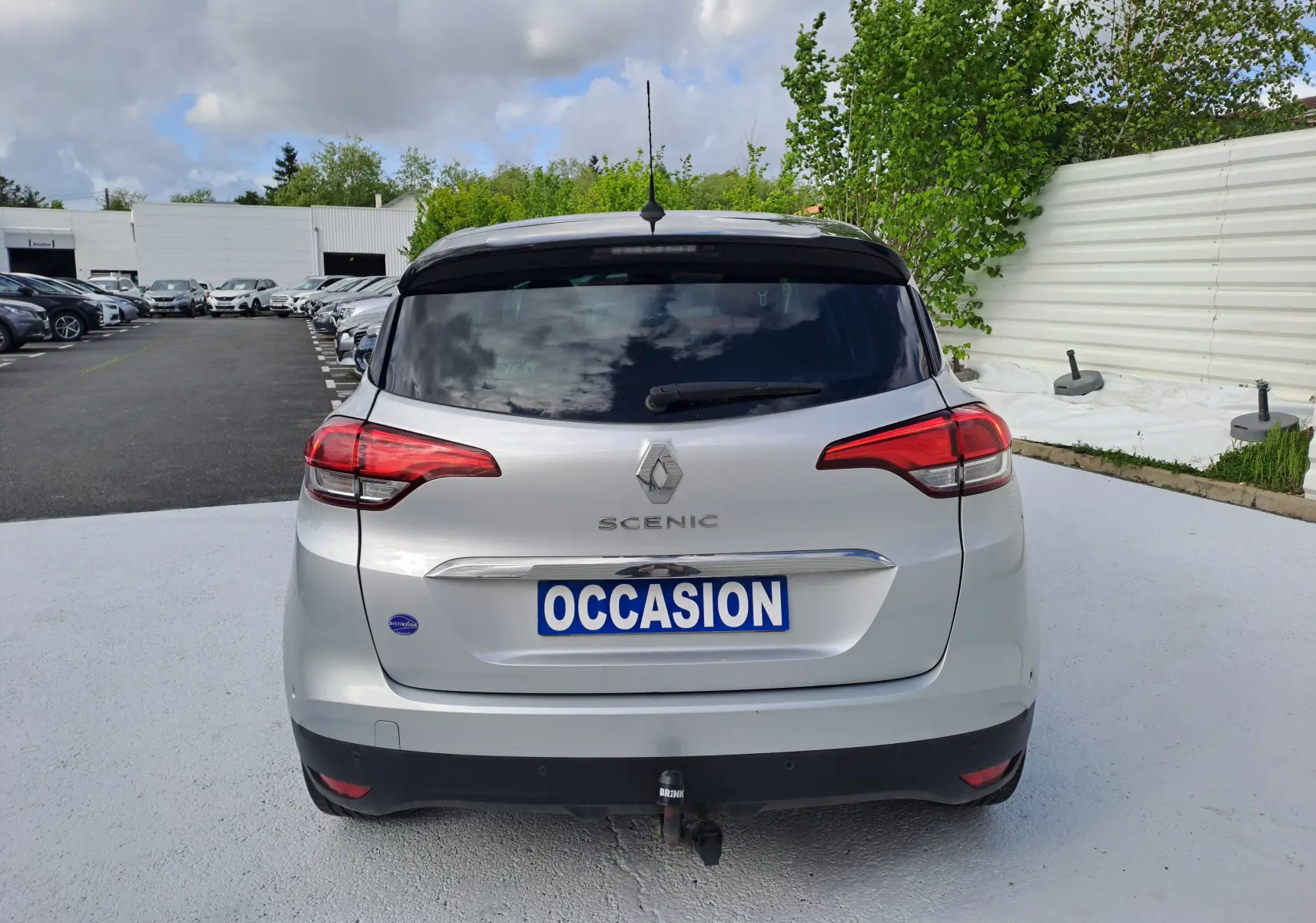 Vue arrière d'un Renault Scénic IV gris platine avec toit noir, plaque "OCCASION" et attelage visible.