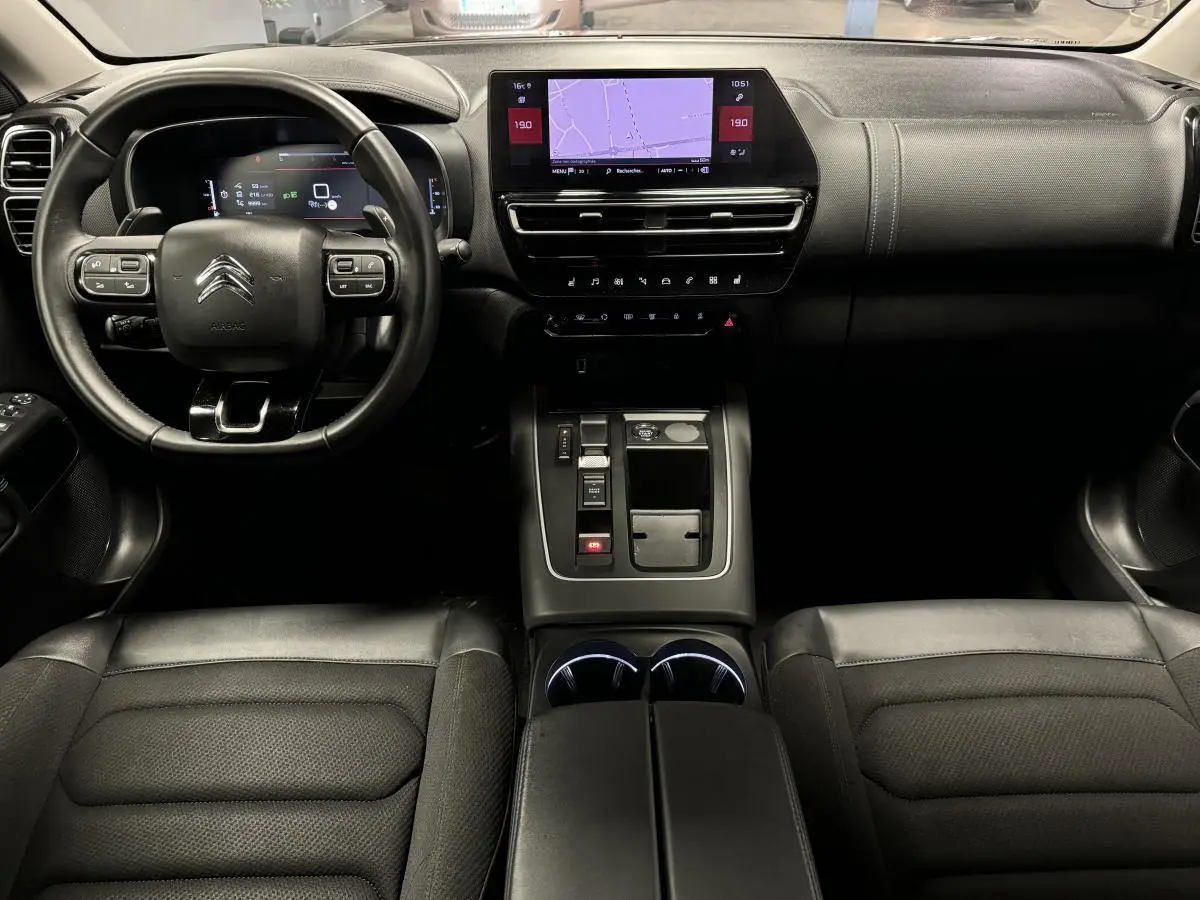 Vue intérieure avant du Citroën C5 Aircross noir avec tableau de bord numérique et console centrale moderne.