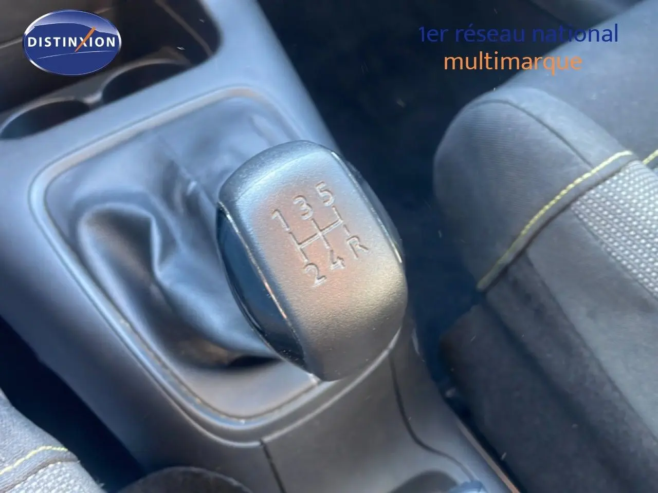 Gros plan sur le levier de vitesses manuel noir et tissu de siège gris avec surpiqûres jaunes dans une Citroën C3 blanche.