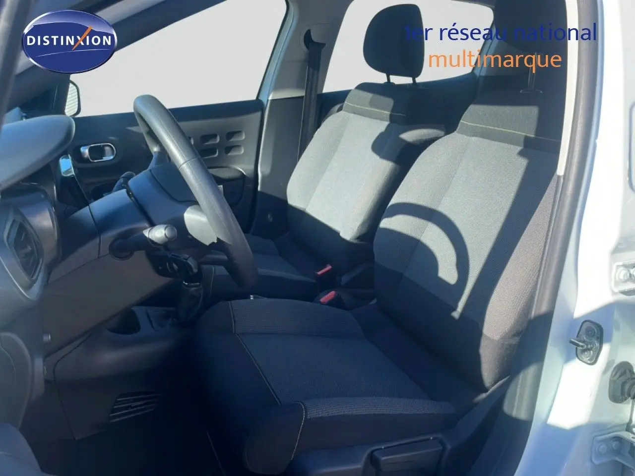 Intérieur côté conducteur d'une Citroën C3 blanche banquise 2020, sièges tissu gris et volant multifonction.