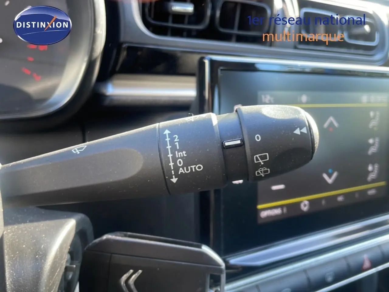 Gros plan sur la commande d'essuie-glace à gauche du volant dans l'habitacle d'une Citroën C3 blanc banquise.