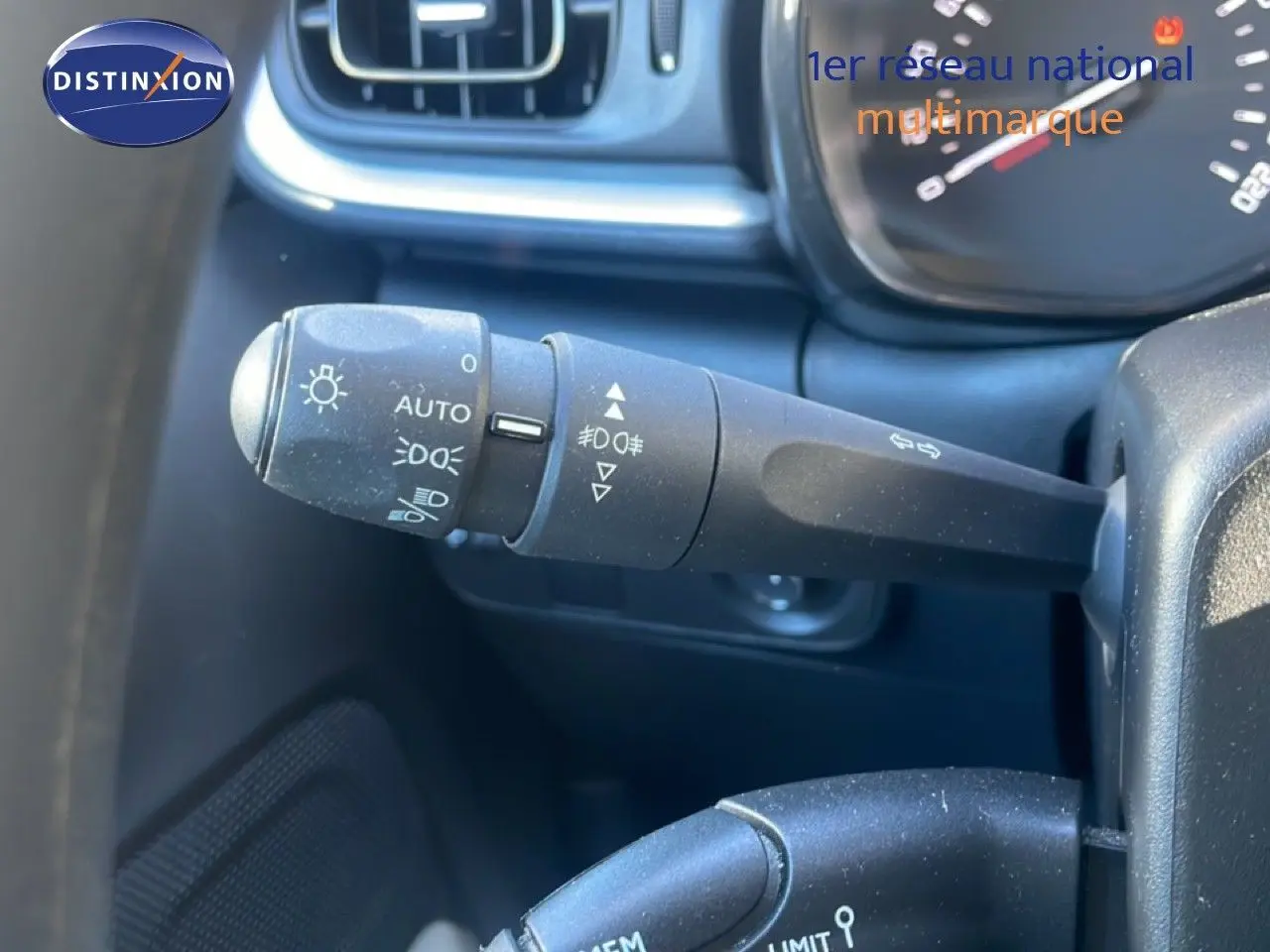 Gros plan sur la commande des phares et clignotants dans l'habitacle noir d'une Citroën C3 blanche banquise 2020.