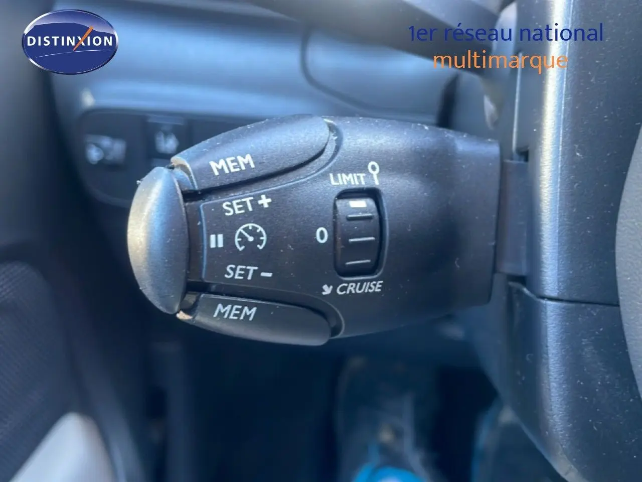Gros plan sur la commande de régulateur de vitesse noire dans l'habitacle d'une Citroën C3 blanc banquise.