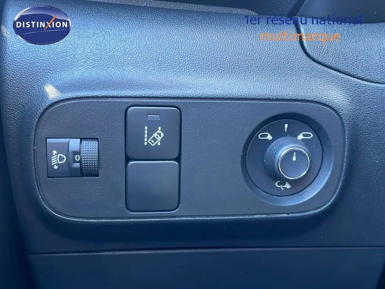 Gros plan sur les commandes noires de réglage des rétroviseurs et des phares dans une Citroën C3 blanc banquise de 2020.