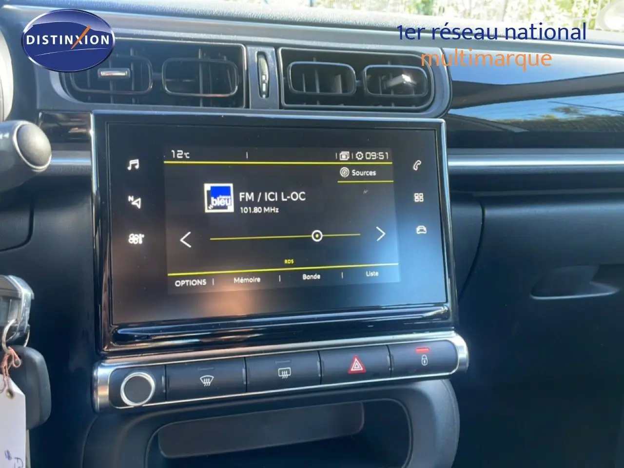 Vue rapprochée de la console centrale de la Citroën C3 blanche, avec écran tactile affichant une radio FM.