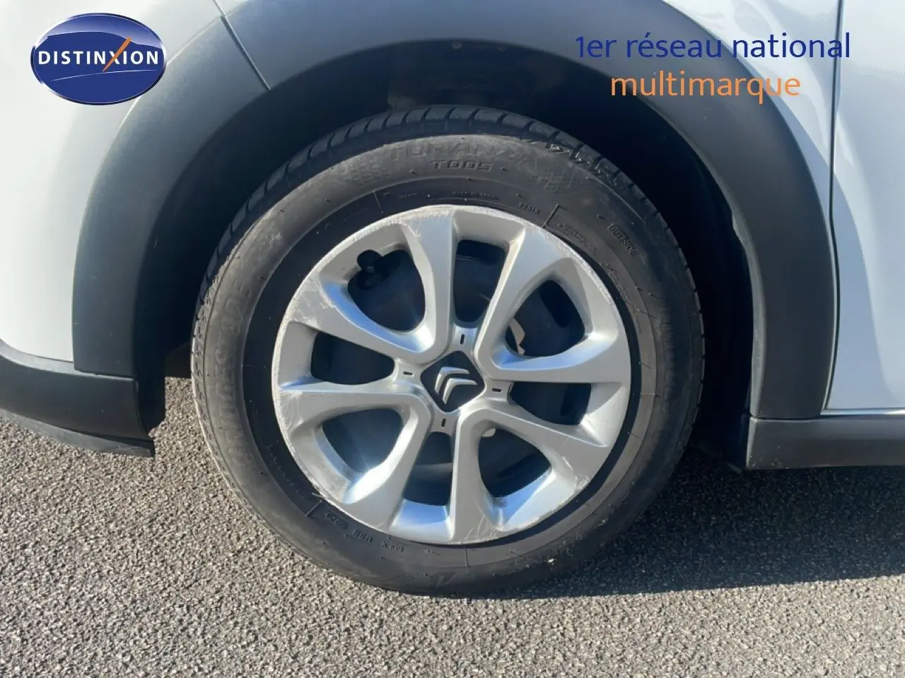 Gros plan sur la roue avant droite d'une Citroën C3 blanc banquise avec jante en alliage distinctive.