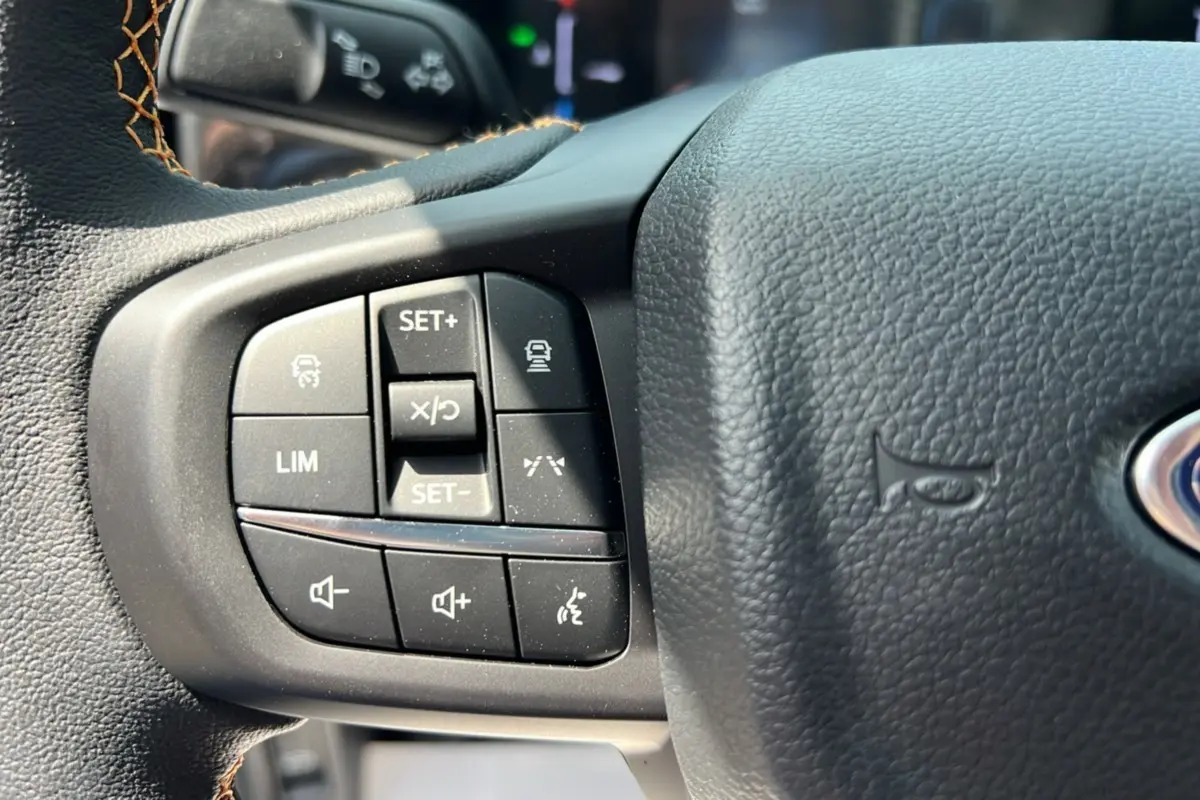 Gros plan sur les commandes multifonctions du volant en cuir noir du Ford Ranger Wildtrak Plus 2025.