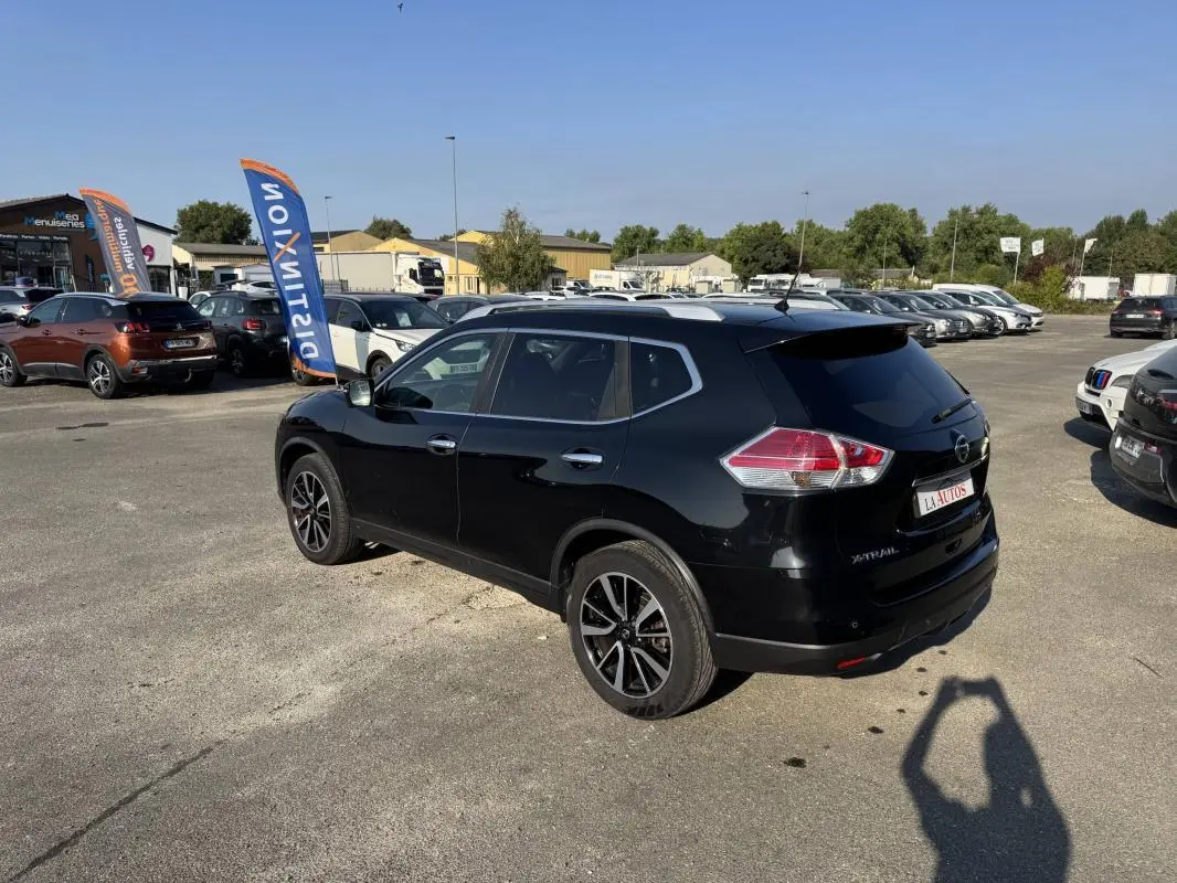 Nissan X-Trail noir vue 3/4 arrière droit sur parking, jantes alliage et vitres teintées visibles.