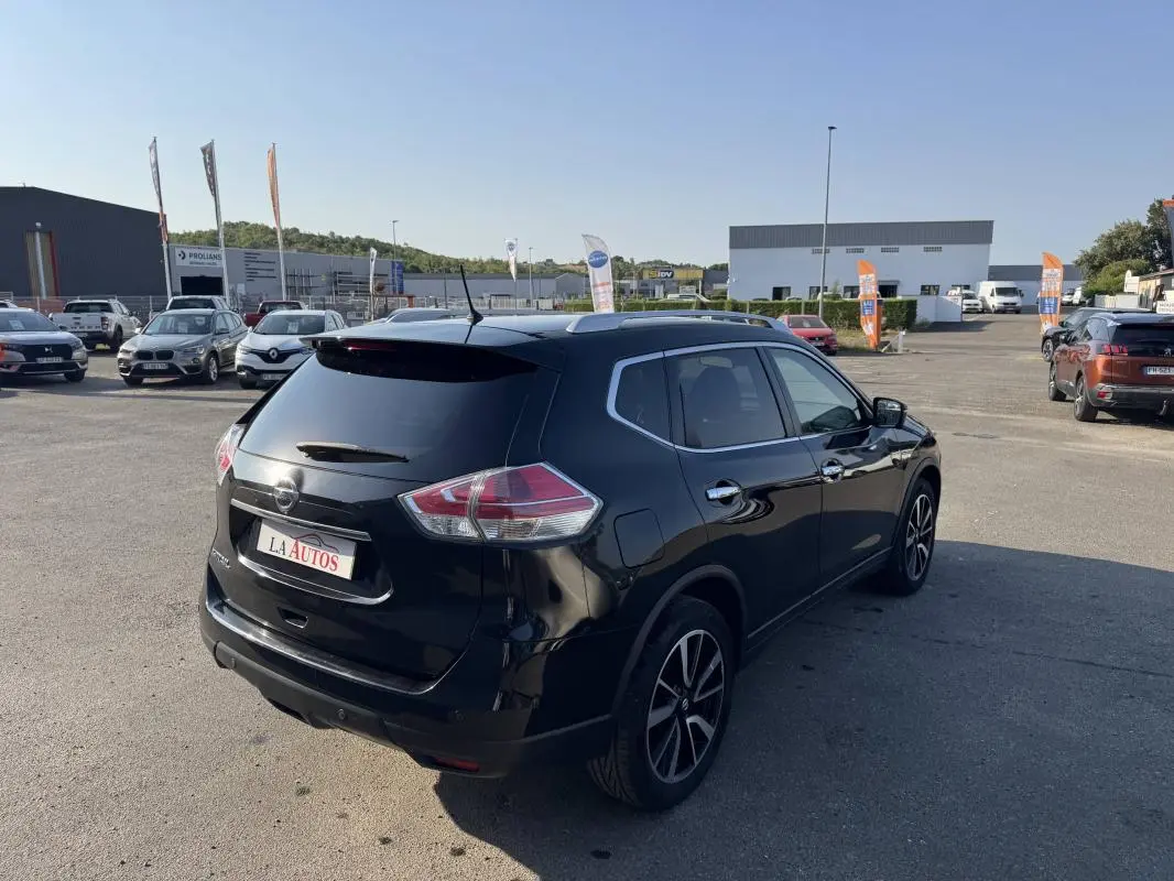Nissan X-Trail noir vue 3/4 arrière droit, avec jantes alliage et vitres teintées, sur parking extérieur ensoleillé.