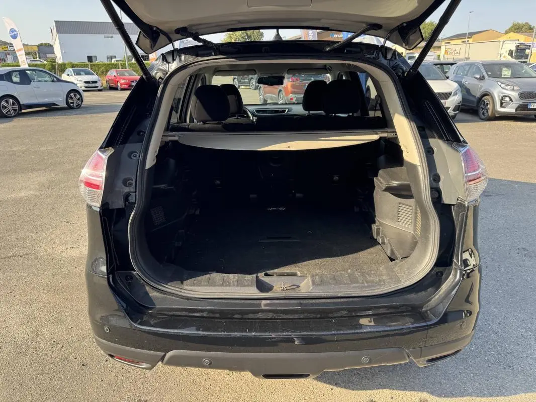 Vue arrière du coffre ouvert d'un Nissan X-Trail noir 2017, montrant l'espace de chargement et l'intérieur sombre.