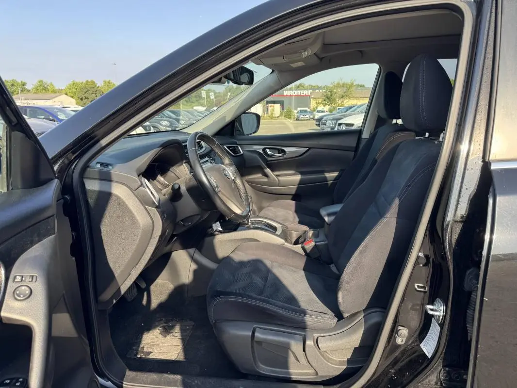 Intérieur avant droit du Nissan X-TRAIL III noir 2017, montrant les sièges tissu et le tableau de bord avec volant.