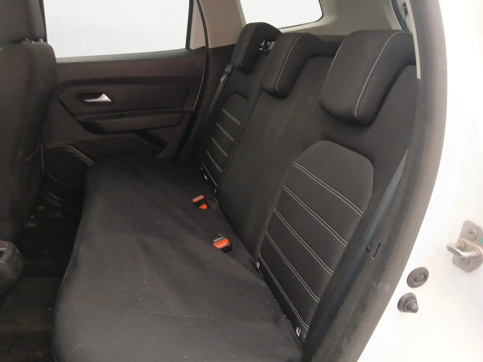 Vue intérieure côté conducteur du Dacia Duster blanc 2021, sièges noirs avec logo Duster brodé.