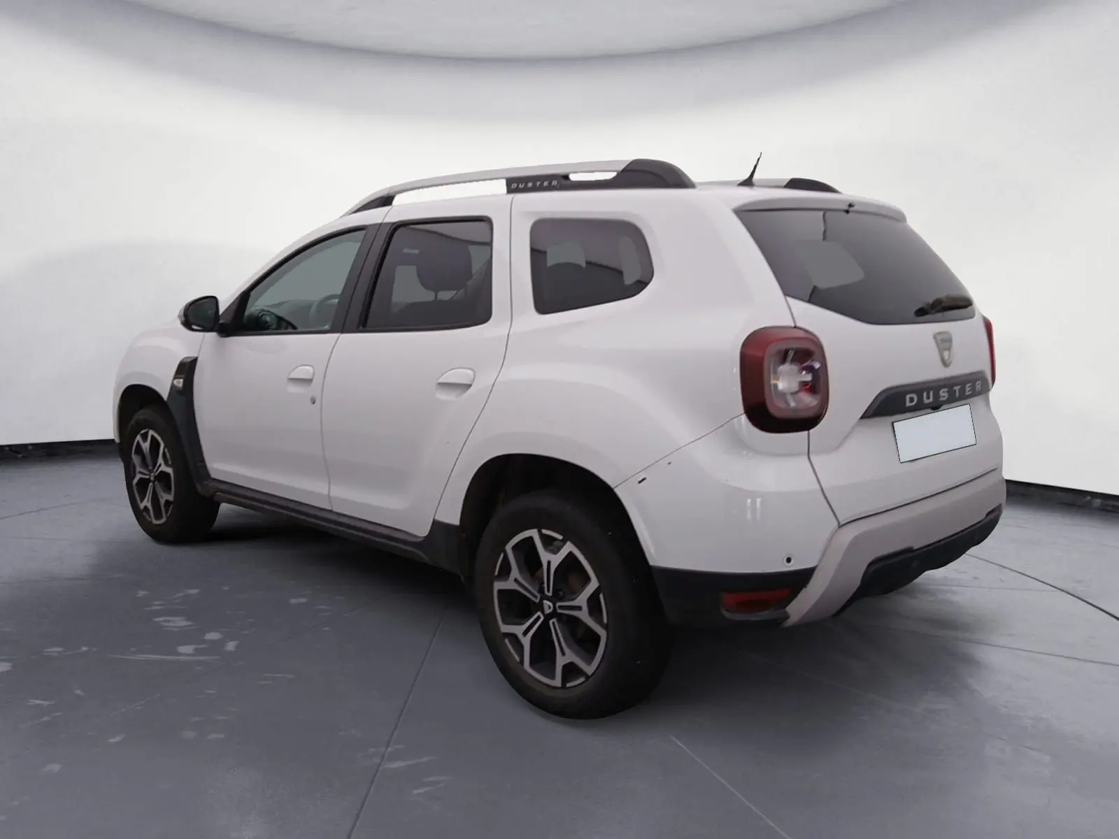 Vue arrière ouverte du Dacia Duster blanc 2021, coffre spacieux visible avec hayon relevé en extérieur.