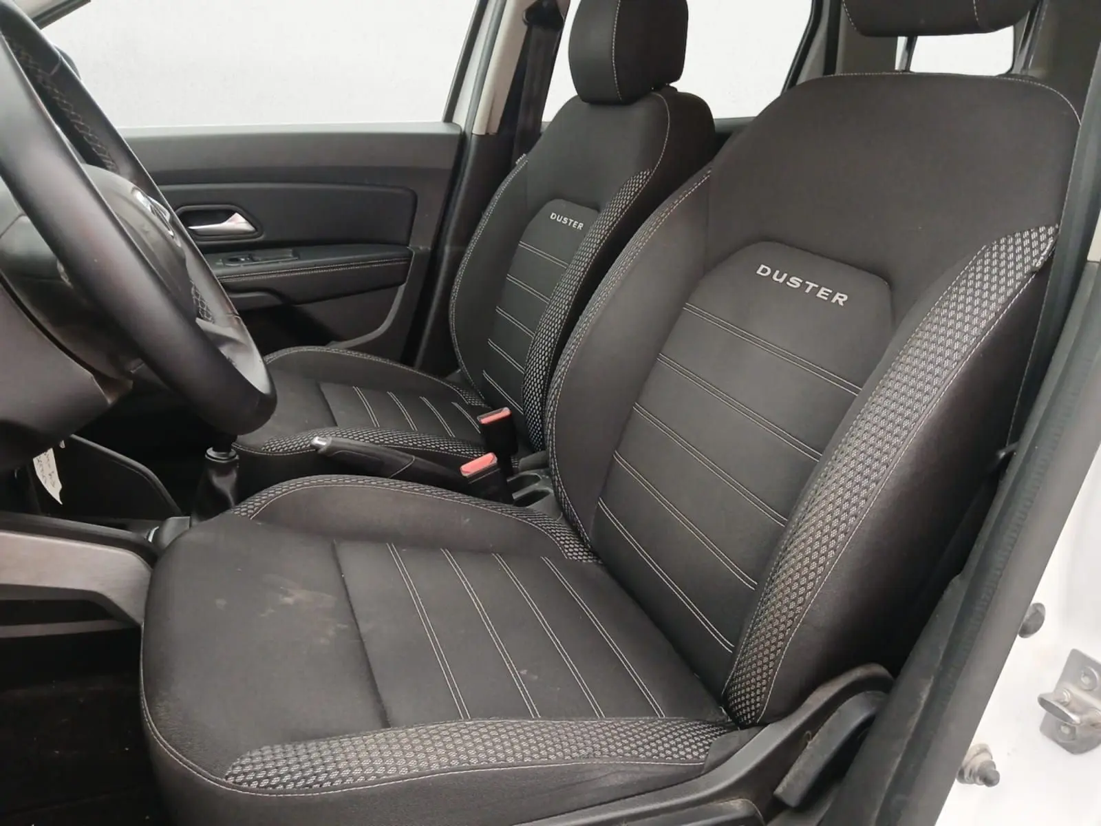 Profil côté gauche d'un Dacia Duster blanc 2021, version 4x2 Prestige avec jantes alliage noires et toit noir.