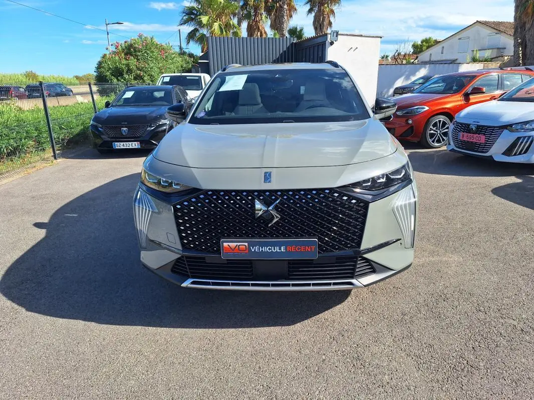 Vue avant d'un DS7 gris 2024 avec calandre distinctive et feux LED, stationné en extérieur sur un parking.