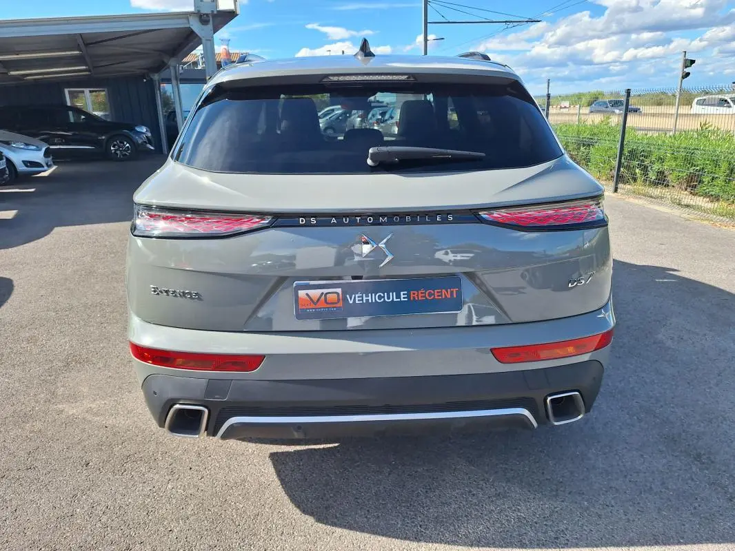Vue arrière du DS7 gris 2024 avec feux LED étirés et double sortie d'échappement carrée visible.