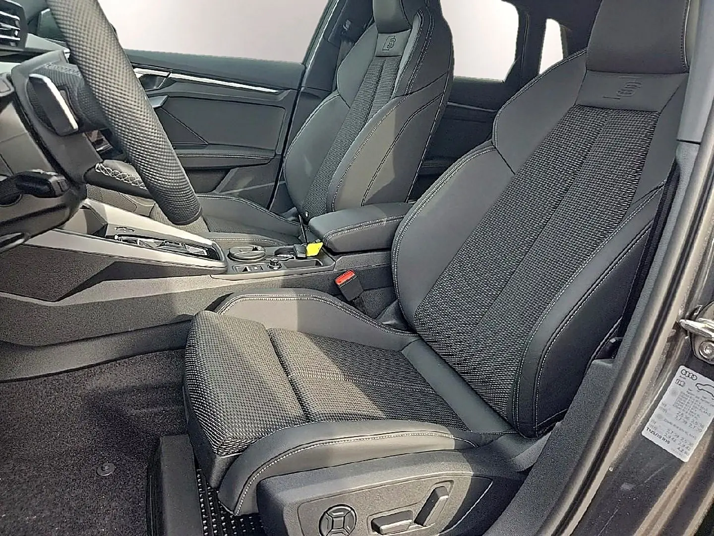 Vue intérieure côté conducteur de l'Audi A3 Sportback 2026 avec sièges sport noirs et volant cuir multifonction.