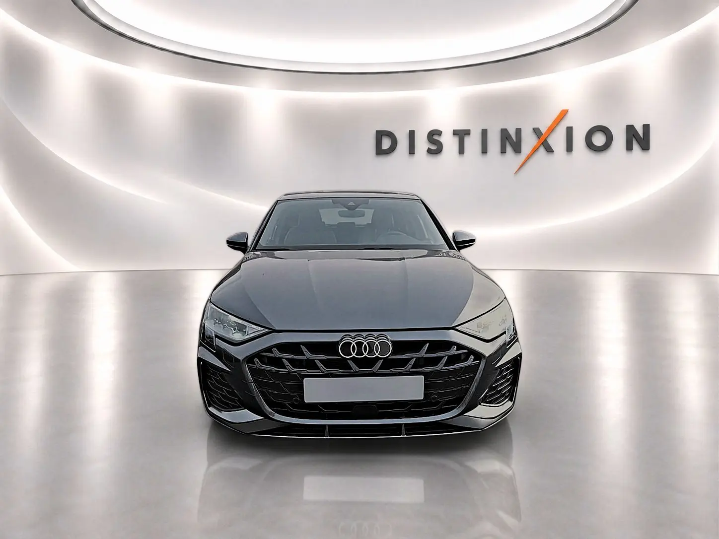 Audi A3 Sportback gris Daytona vue de face dans un showroom avec logo Distinxion en arrière-plan.