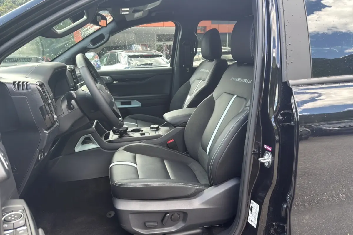 Vue intérieure côté conducteur du Ford Ranger 2.3 PHEV noir agate, sièges Stormtrak en cuir et alcantara avec surpiqûres grises.