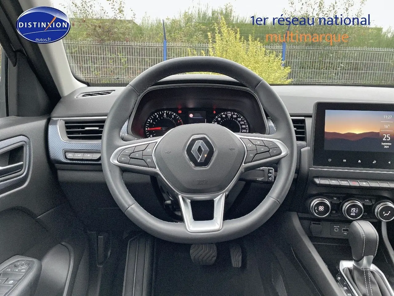 Vue intérieure centrée sur le volant Renault Arkana noir, tableau de bord et écran tactile lumineux en arrière-plan.