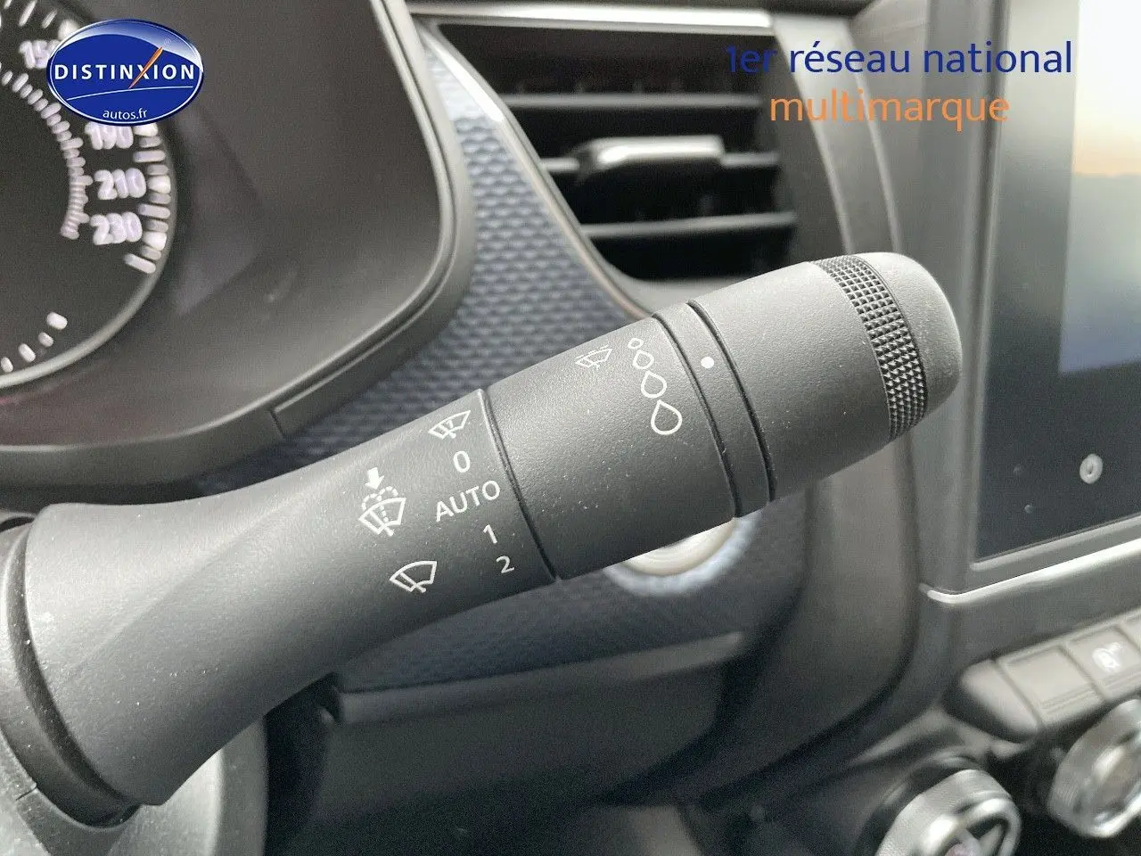 Gros plan sur la commande d'essuie-glace du Renault Arkana noir métal, avec tableau de bord et écran tactile en arrière-plan.