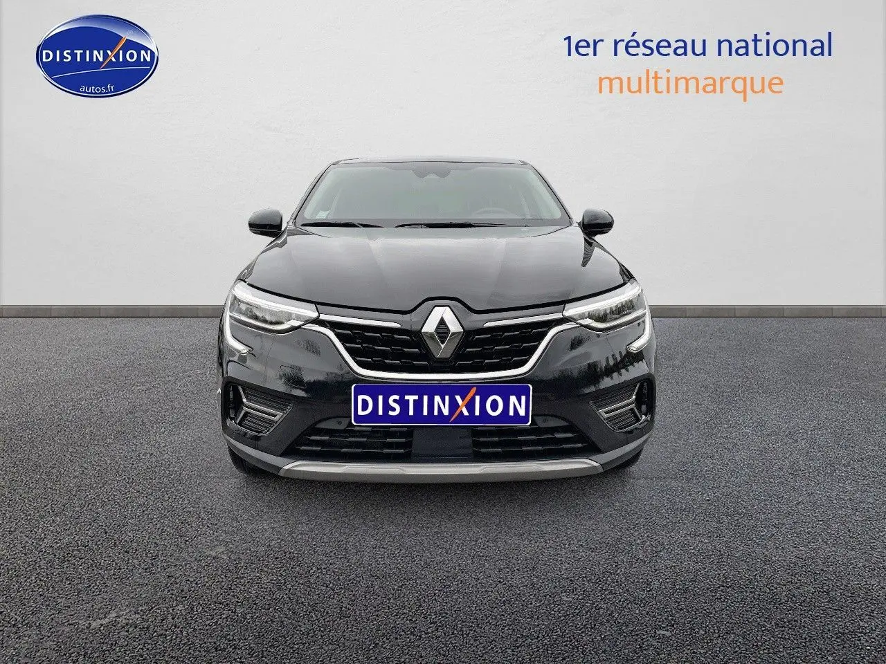Vue frontale d'un Renault Arkana noir métal 2023 avec calandre chromée et phares LED allumés.
