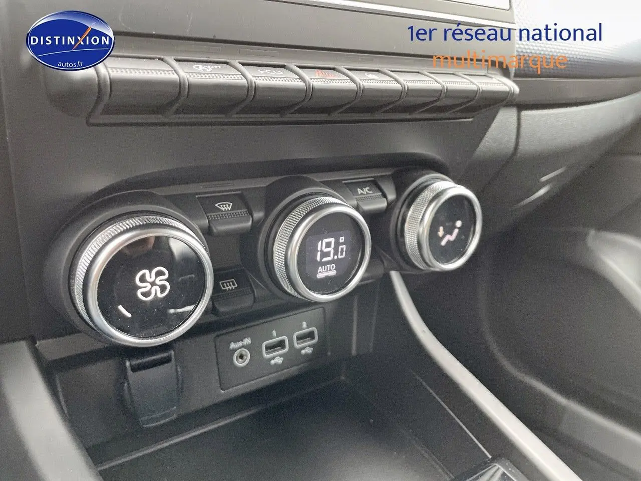 Gros plan sur la console centrale de la Renault Arkana noire, montrant les commandes de climatisation et ports USB.