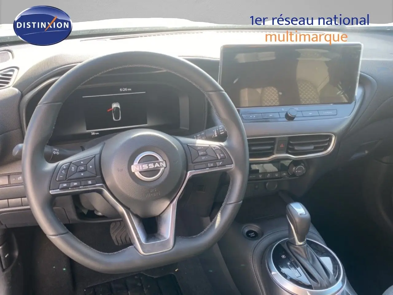 Vue intérieure du tableau de bord du Nissan Juke 2025, volant cuir noir et écran tactile central.