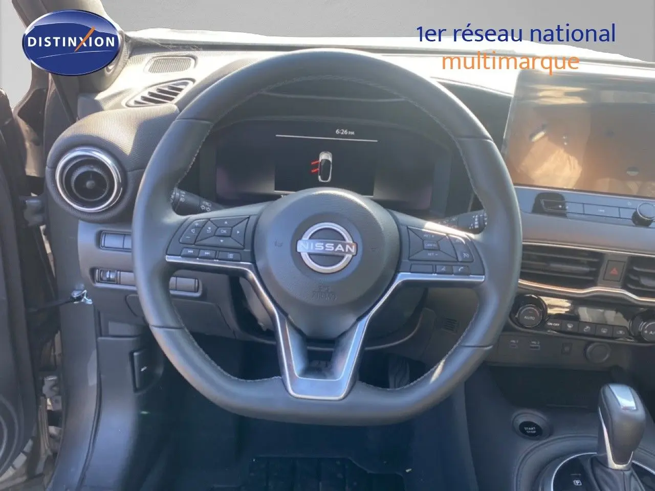 Vue intérieure centrée sur le volant Nissan du Juke 2025, avec tableau de bord et console en arrière-plan.