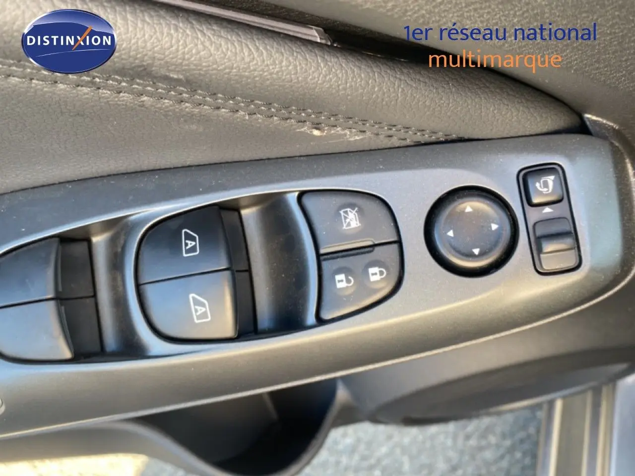 Gros plan sur les commandes de lève-vitres et réglages des rétroviseurs côté conducteur du Nissan Juke gris squale métal 2025.