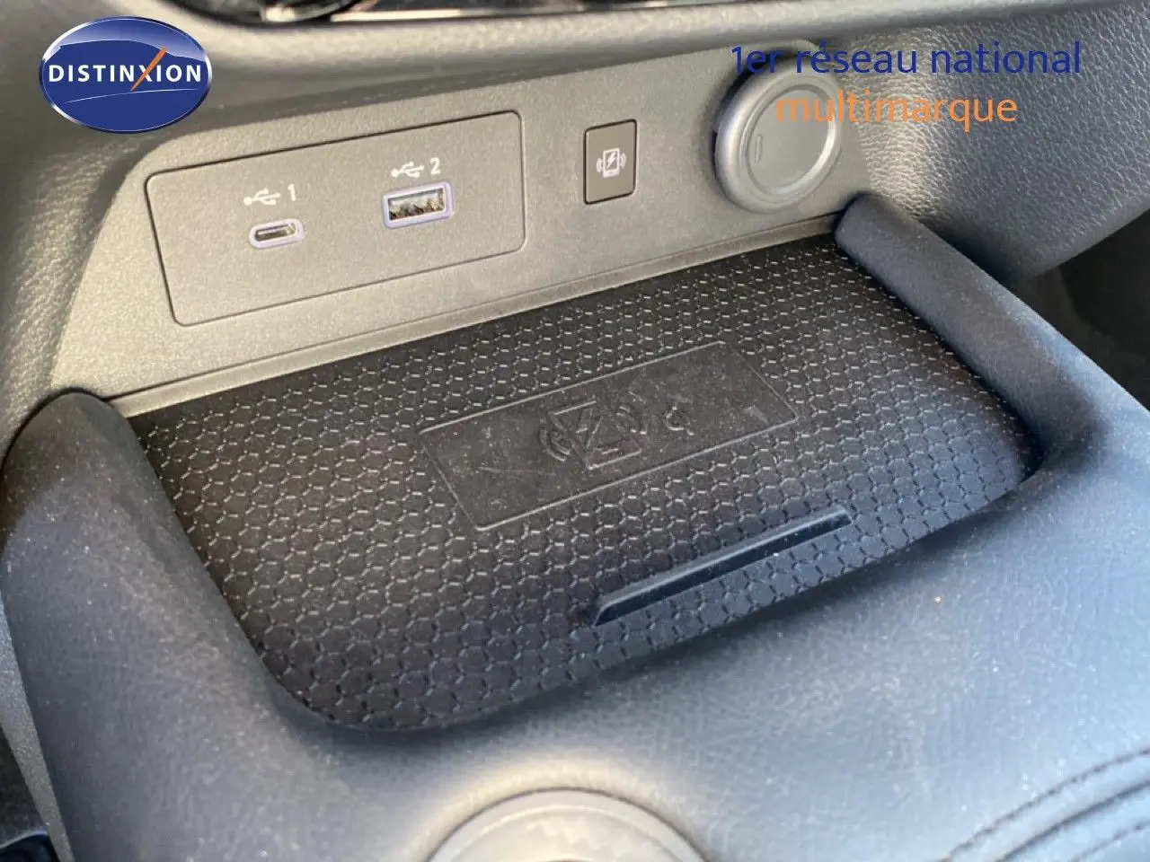 Gros plan sur la console centrale du Nissan Juke 2025, montrant les ports USB et la zone de charge sans fil.