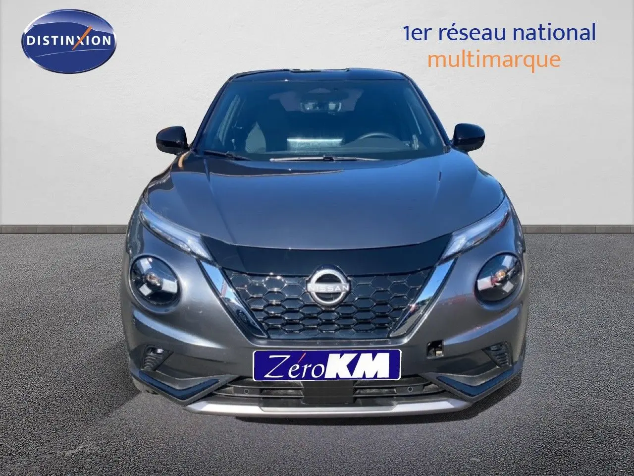 Vue avant d'un Nissan Juke 1.6 Full Hybrid gris squale métal avec toit noir, mettant en valeur sa calandre hexagonale distinctive.