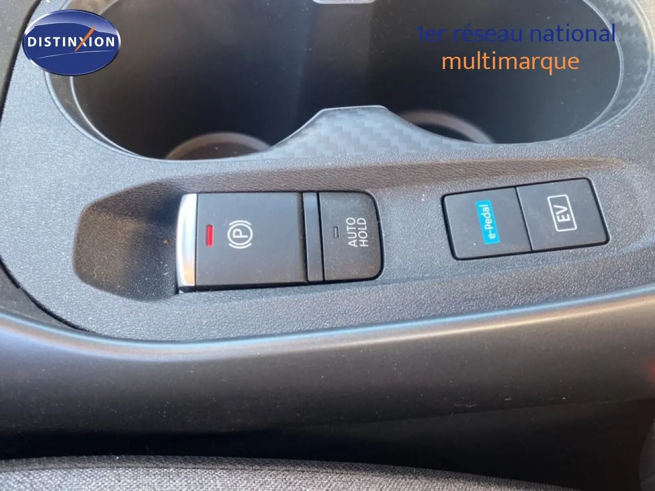 Gros plan sur la console centrale du Nissan Juke 2025, boutons de frein à main électrique et modes e-Pedal et EV visibles.
