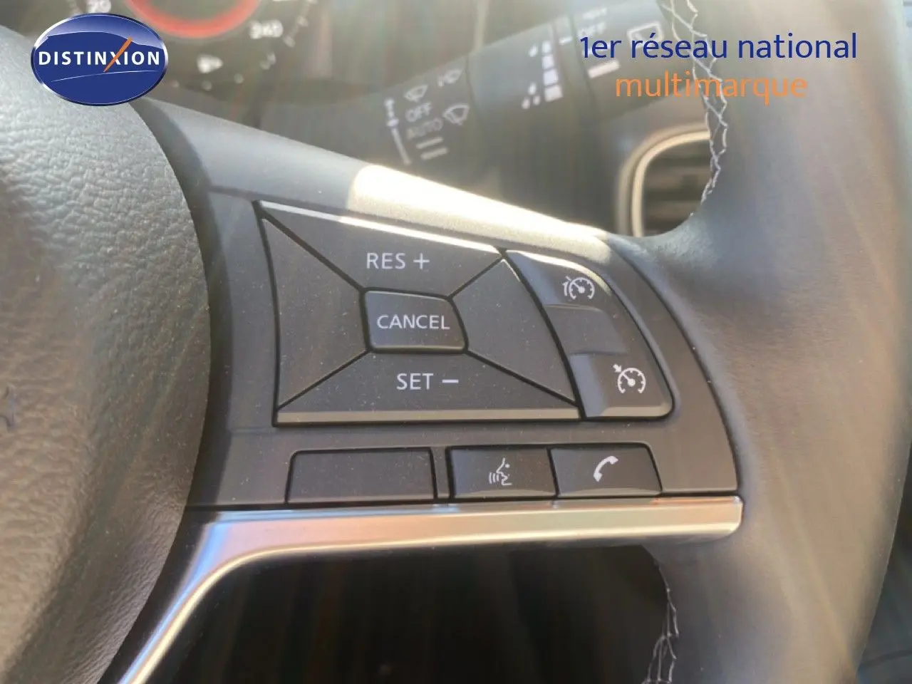 Gros plan sur les commandes au volant à droite du Nissan Juke 2025, finition N-Sport, avec cuir noir et boutons de régulateur de vitesse.