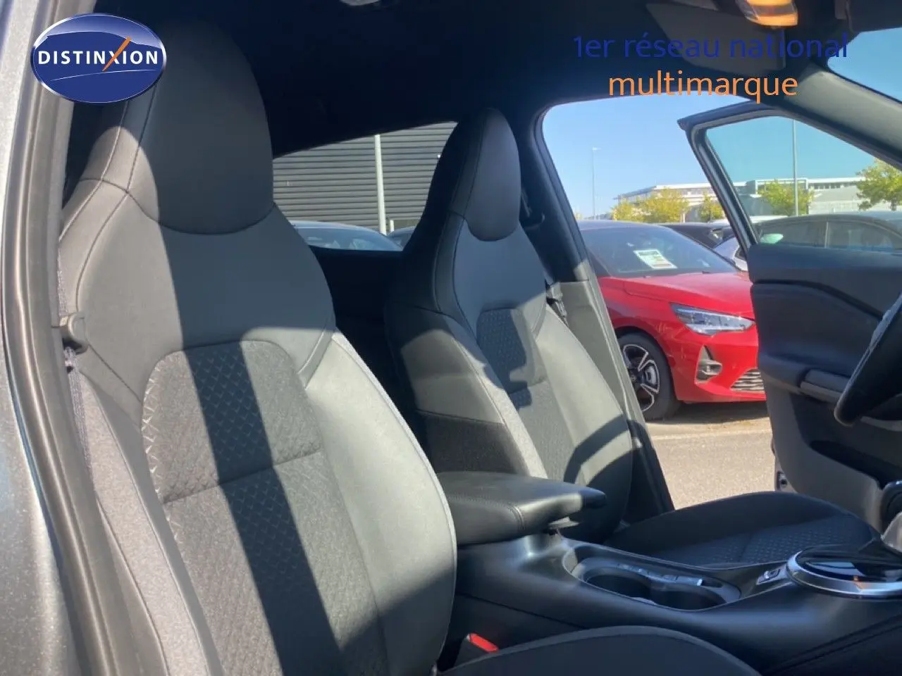 Vue intérieure côté gauche montrant les sièges avant en tissu noir du Nissan Juke 1.6 Full Hybrid 2025.