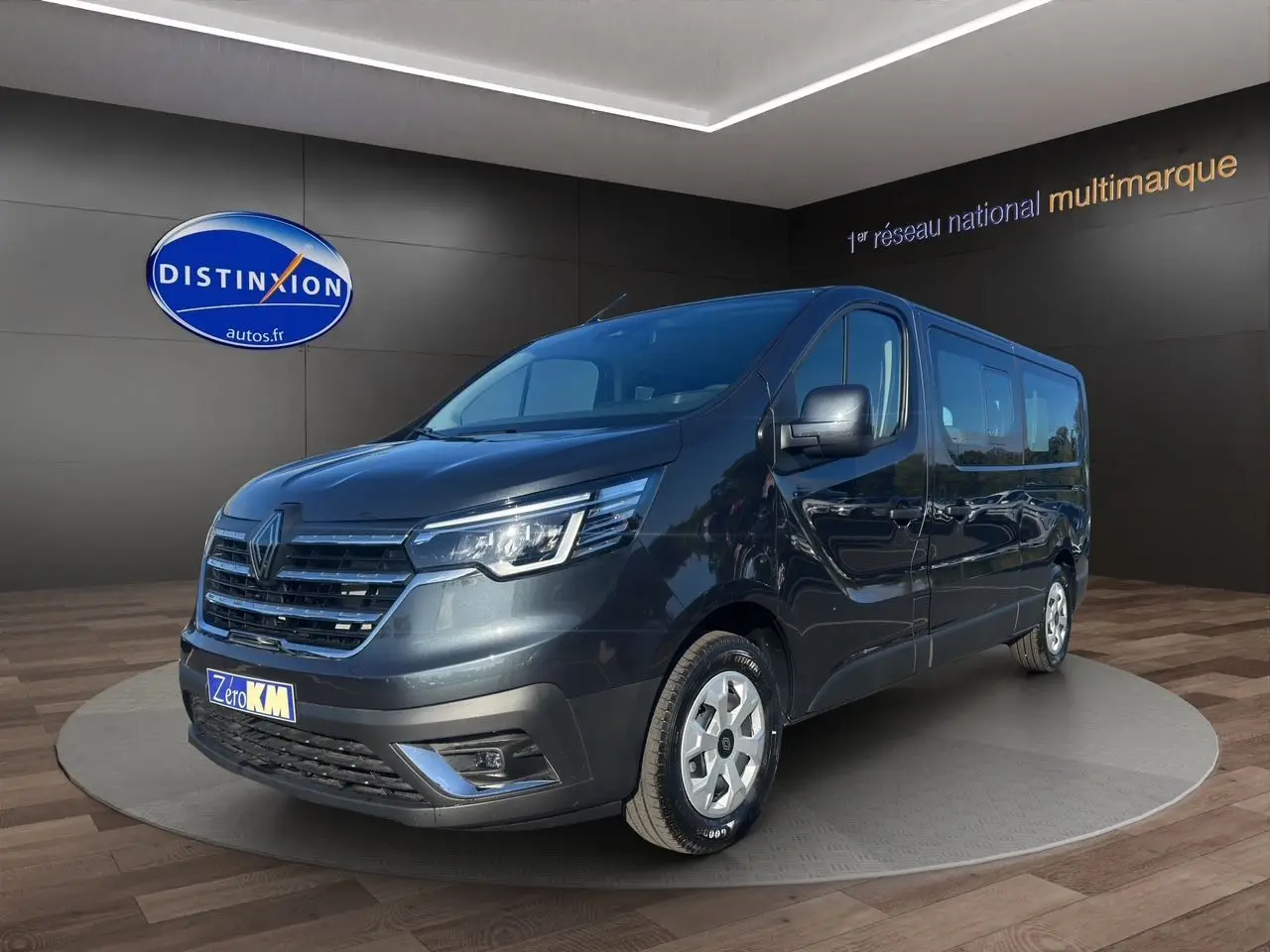 Renault Trafic Combi gris comète en vue 3/4 avant droit, avec portes latérales vitrées et jantes tôlées 16 pouces.