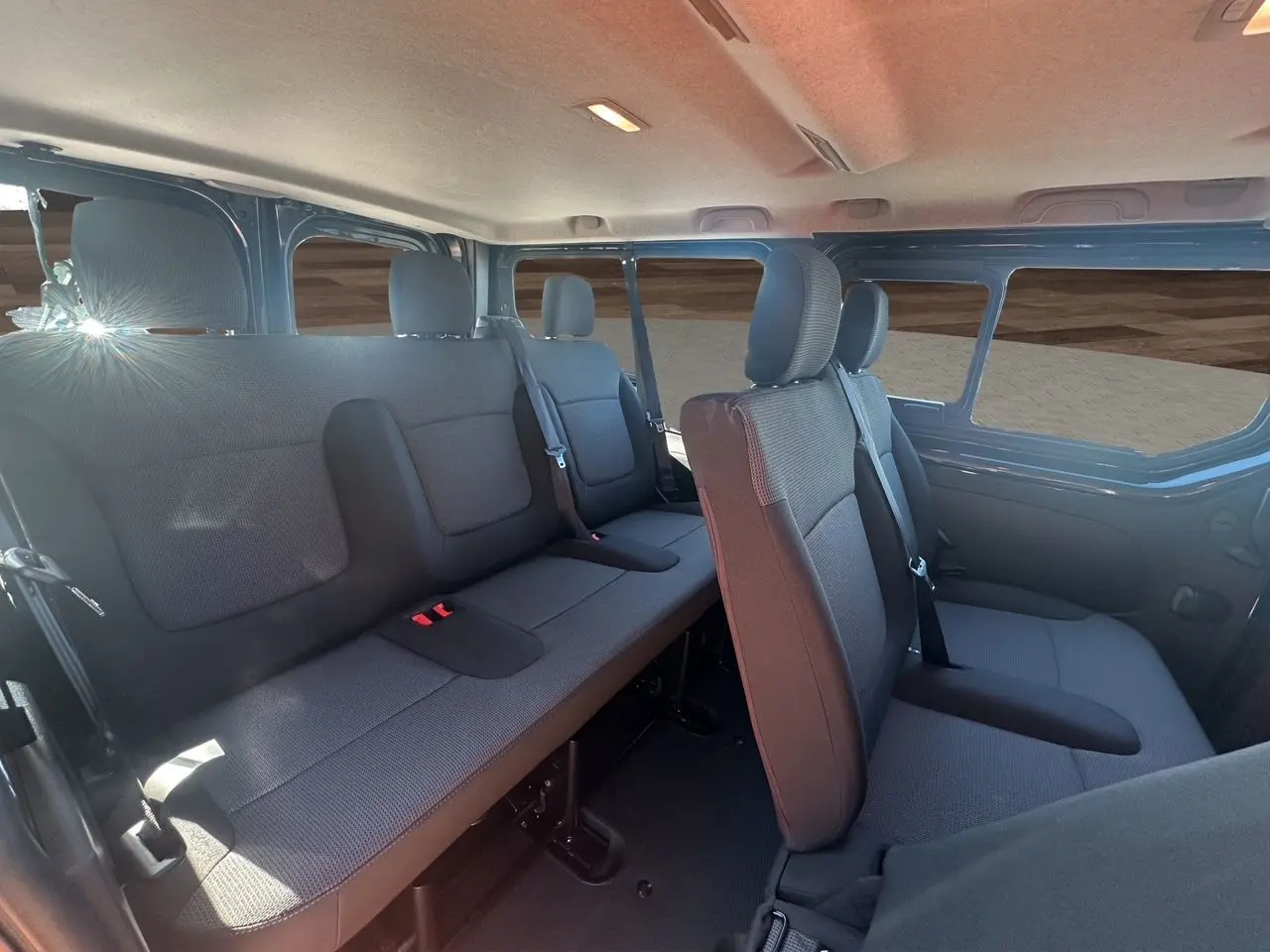 Intérieur du Renault Trafic Combi gris comète, vue latérale droite sur les sièges tissu noir et banquette arrière.