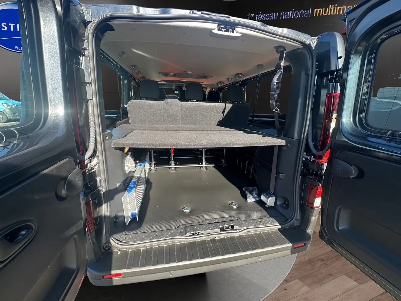 Vue arrière ouverte du Renault Trafic Combi gris comète, montrant l'espace de chargement et les sièges arrière.