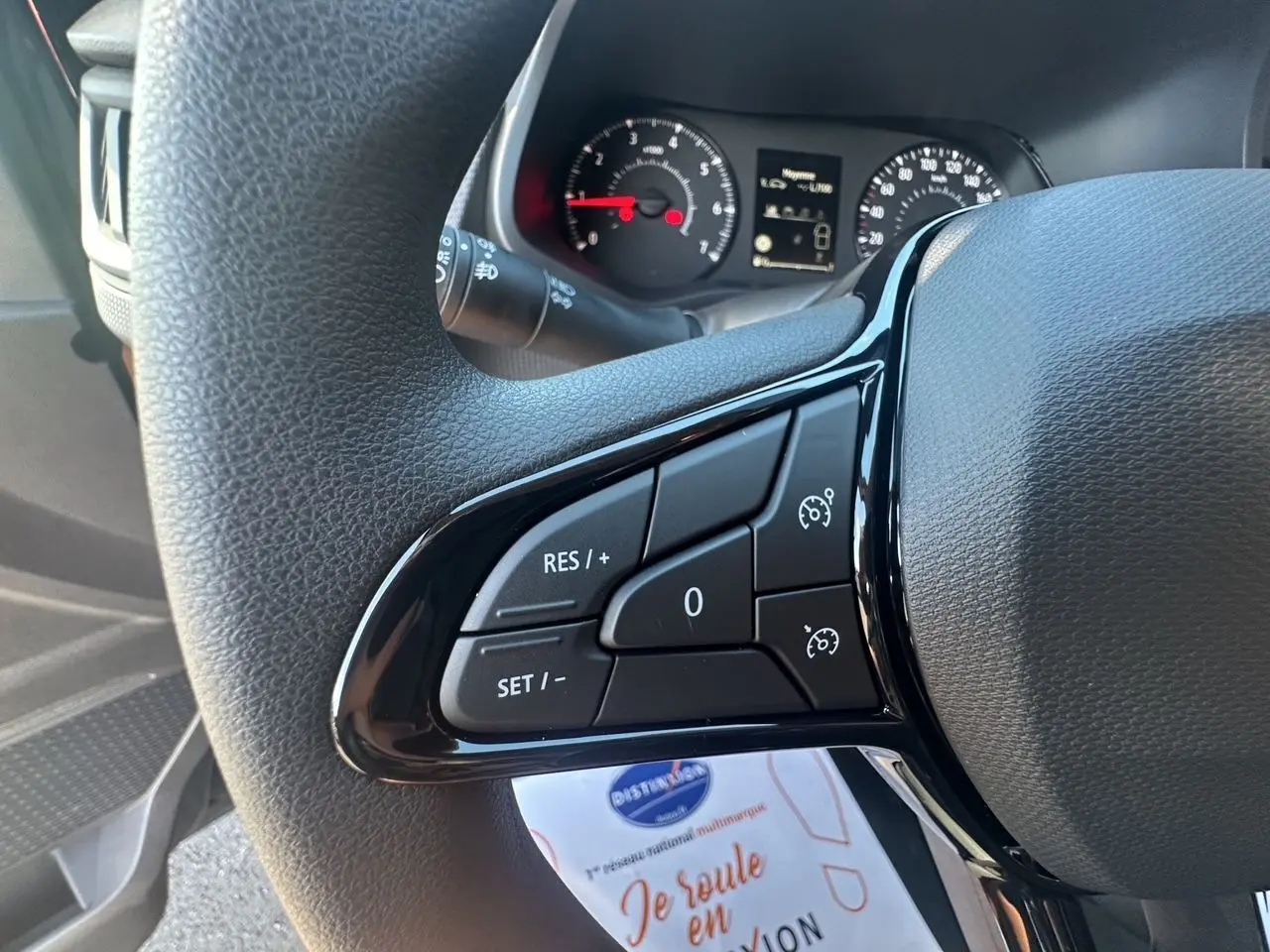 Gros plan sur les commandes du régulateur de vitesse au volant d'un Renault Trafic Combi 2025, intérieur noir.