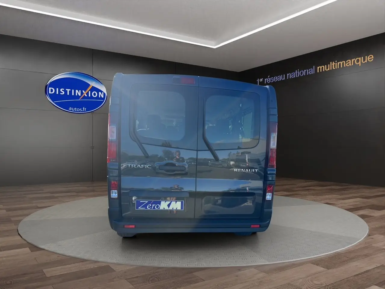 Vue arrière d'un Renault Trafic Combi gris comète avec portes battantes et logo Zero KM visible.
