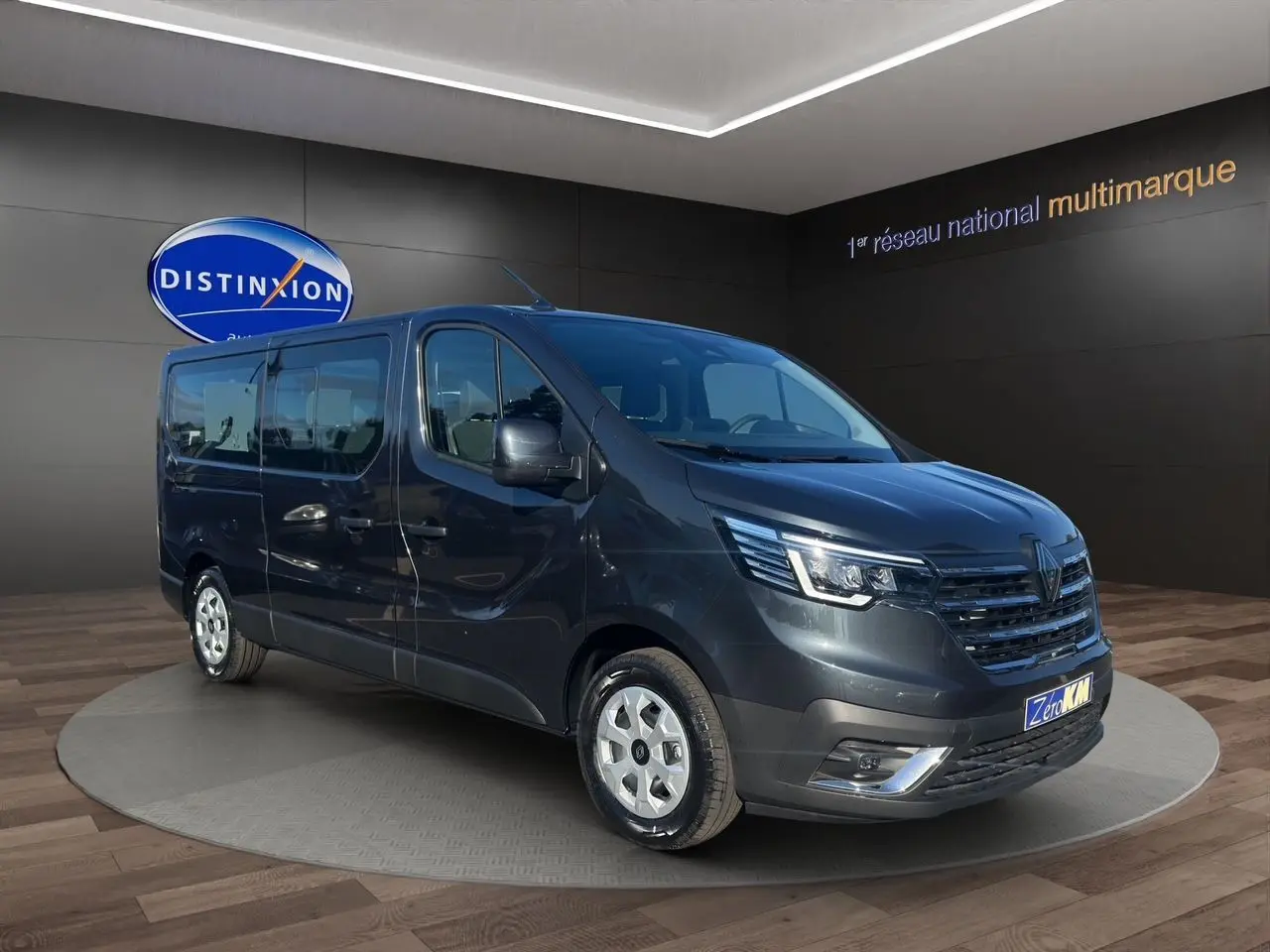 Renault Trafic Combi gris comète vu en 3/4 avant droit, avec portes latérales vitrées et jantes tôlées 16 pouces.