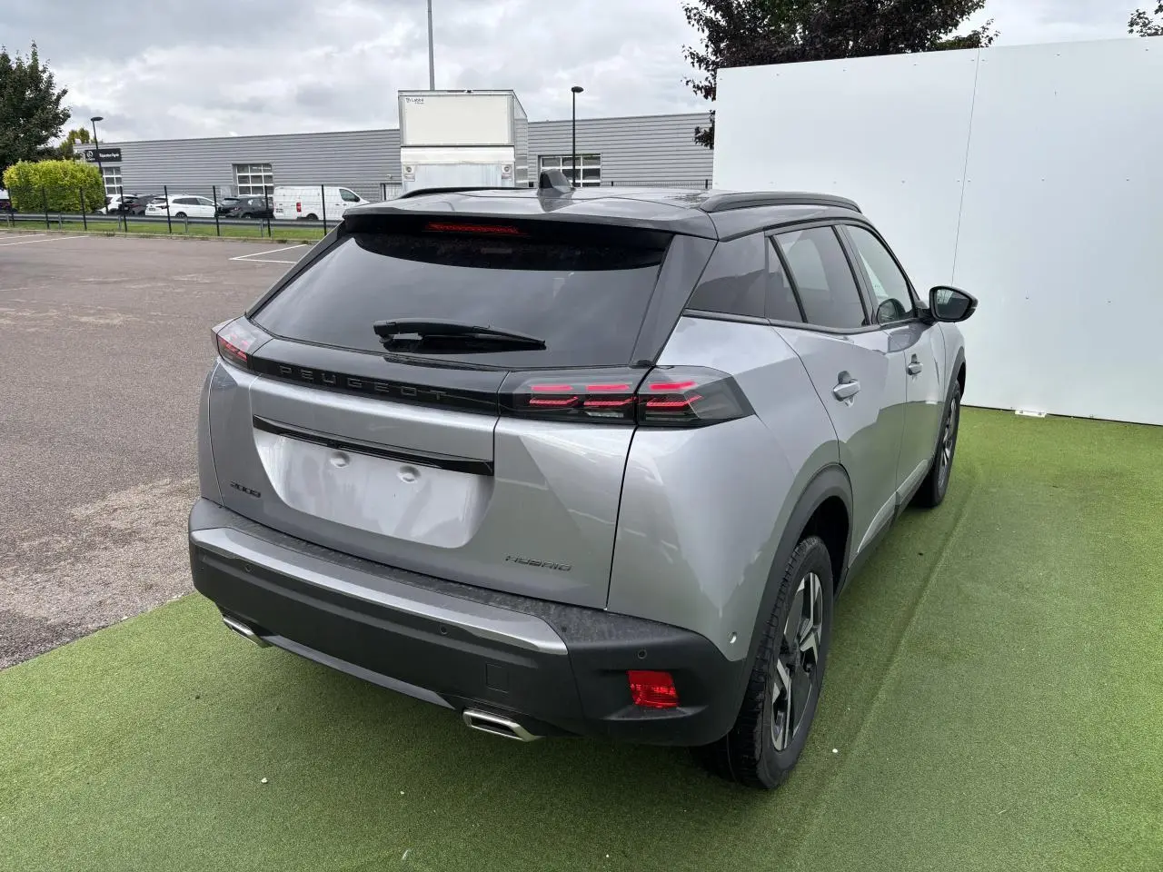 Vue 3/4 arrière droite d'un Peugeot 2008 gris Artense avec toit noir, feux arrière LED à 3 griffes et double sortie d'échappement chromée.