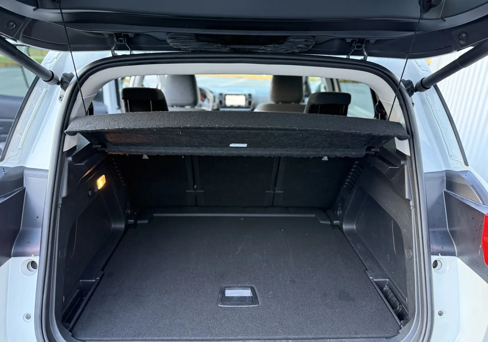 Coffre ouvert vu de l'arrière d'un Citroën C5 Aircross blanc nacré, montrant un espace de chargement spacieux et propre.
