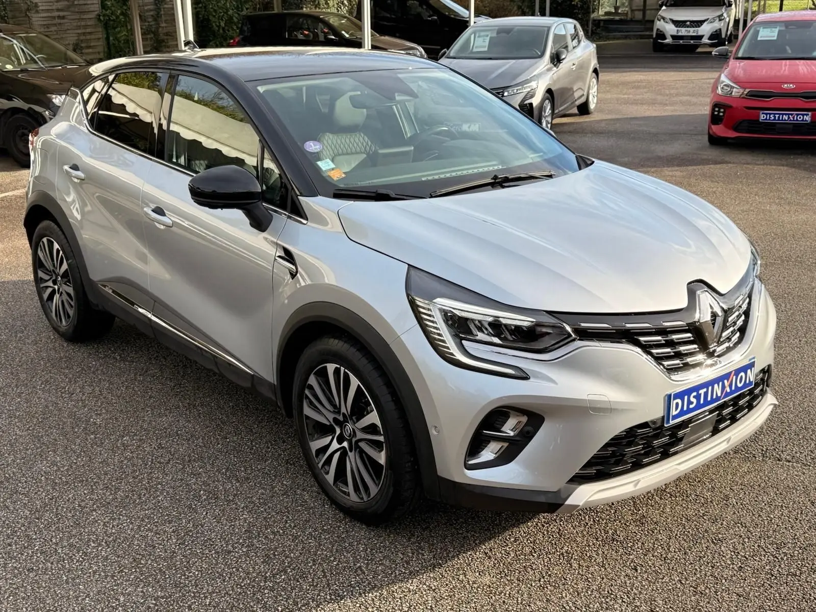 Renault Captur gris Highland en 3/4 avant droit, avec toit noir et jantes alliage distinctives.